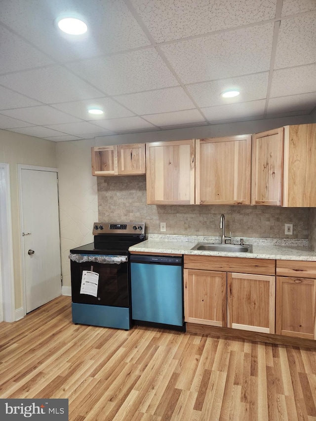 kitchen with sink, a drop ceiling, backsplash, appliances with stainless steel finishes, and light wood-type flooring