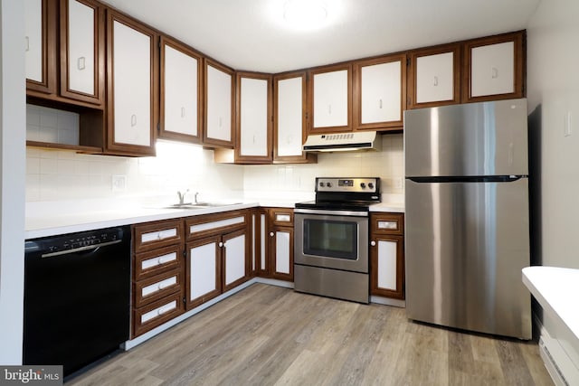 kitchen with tasteful backsplash, sink, light wood-type flooring, and appliances with stainless steel finishes