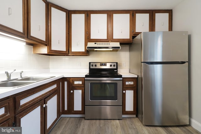 kitchen with stainless steel appliances, tasteful backsplash, light hardwood / wood-style floors, and sink