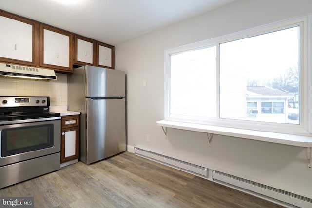 kitchen featuring plenty of natural light, baseboard heating, stainless steel appliances, and tasteful backsplash