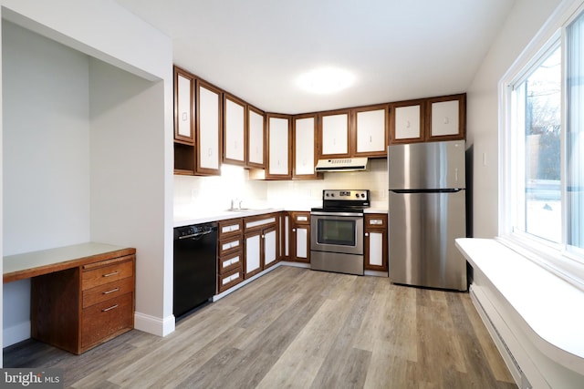 kitchen with backsplash, stainless steel appliances, and light wood-type flooring