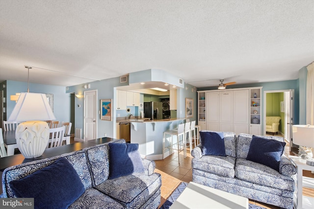 tiled living room featuring ceiling fan and a textured ceiling