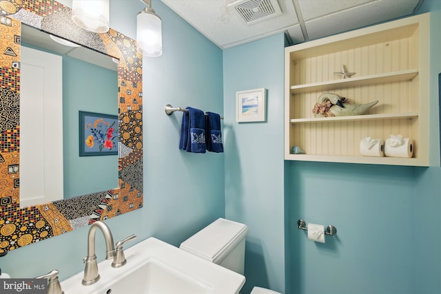 bathroom featuring toilet, a paneled ceiling, and sink