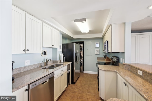 kitchen with sink, a tray ceiling, light stone countertops, appliances with stainless steel finishes, and white cabinets