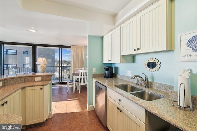 kitchen with light stone countertops, dark tile patterned flooring, dishwasher, sink, and expansive windows