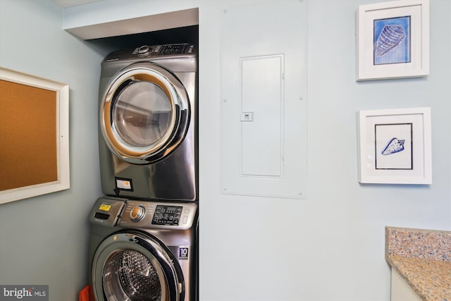 laundry room featuring electric panel and stacked washer / drying machine