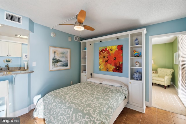 bedroom featuring ceiling fan, sink, a textured ceiling, and tile patterned floors