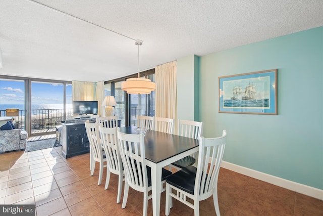 dining room featuring a wall of windows, light tile patterned flooring, and a textured ceiling