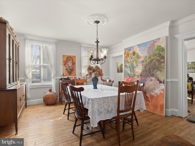 dining area featuring crown molding, light hardwood / wood-style flooring, and a chandelier