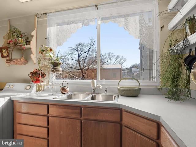 kitchen with washer / clothes dryer, sink, and a healthy amount of sunlight