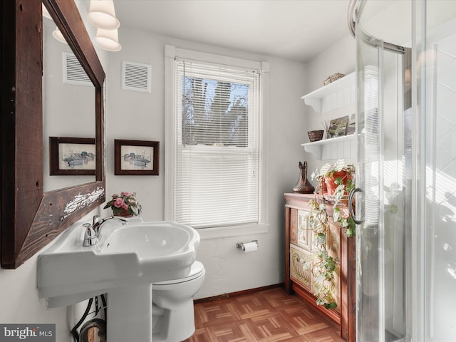 bathroom featuring toilet, a shower with door, and parquet flooring