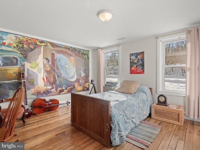 bedroom with multiple windows and light hardwood / wood-style flooring