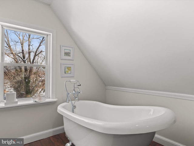 bathroom with wood-type flooring, a tub to relax in, and lofted ceiling