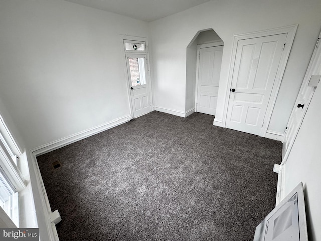 unfurnished bedroom with dark carpet and a closet