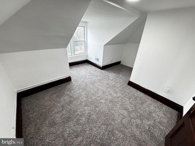 additional living space with dark carpet and lofted ceiling