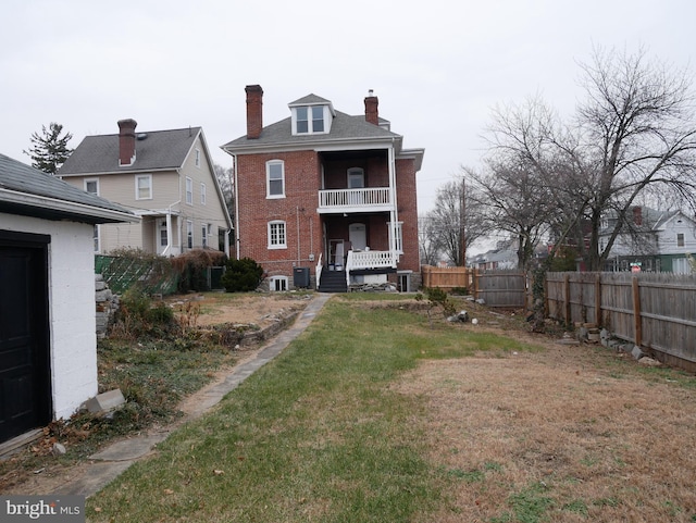 back of house featuring a yard, a balcony, and central AC