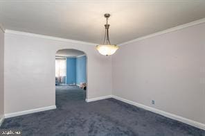 spare room featuring dark carpet and ornamental molding