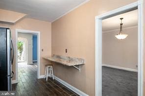 kitchen featuring stainless steel fridge, dark hardwood / wood-style floors, and ornamental molding