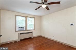 empty room with radiator heating unit, cooling unit, ceiling fan, and dark wood-type flooring