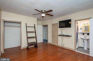 unfurnished bedroom featuring ceiling fan, dark wood-type flooring, connected bathroom, and a closet