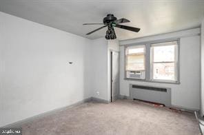 unfurnished room featuring radiator, light carpet, and ceiling fan