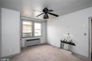 unfurnished room featuring ceiling fan, light colored carpet, and radiator