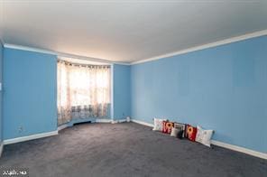 spare room with dark carpet, ornamental molding, and radiator