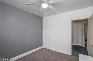 unfurnished bedroom featuring ceiling fan and dark carpet