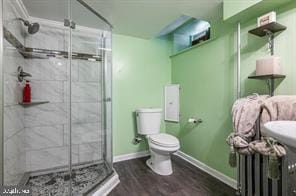 bathroom with toilet, hardwood / wood-style floors, and walk in shower