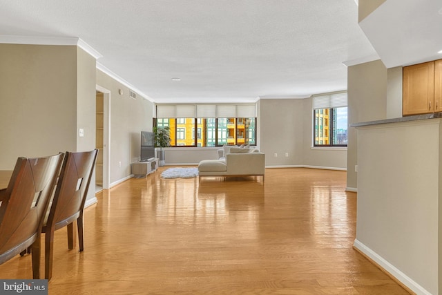 unfurnished living room with light hardwood / wood-style floors, plenty of natural light, and ornamental molding