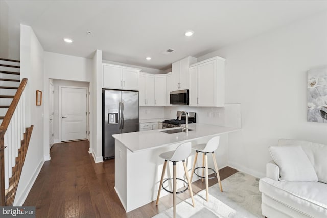 kitchen with kitchen peninsula, stainless steel appliances, white cabinets, and sink