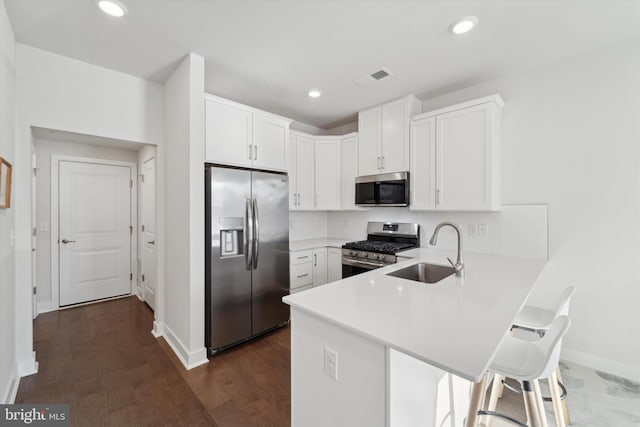 kitchen with white cabinetry, sink, stainless steel appliances, kitchen peninsula, and a breakfast bar area