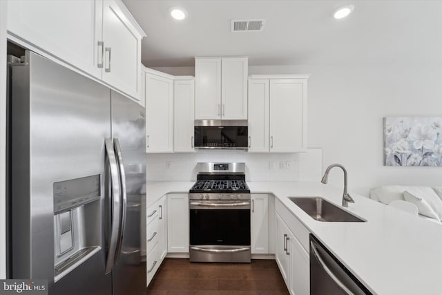 kitchen with appliances with stainless steel finishes, tasteful backsplash, white cabinetry, and sink