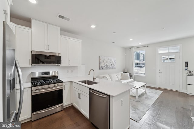 kitchen with kitchen peninsula, sink, white cabinets, and stainless steel appliances