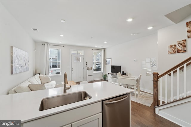 kitchen with dark hardwood / wood-style flooring, white cabinetry, sink, and stainless steel dishwasher