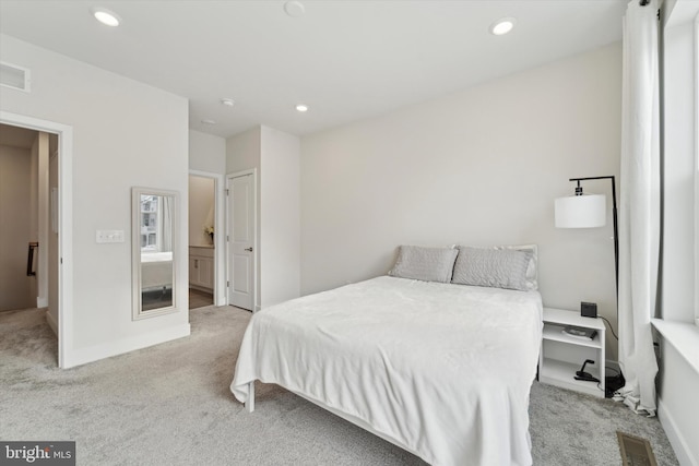 bedroom with light colored carpet and connected bathroom