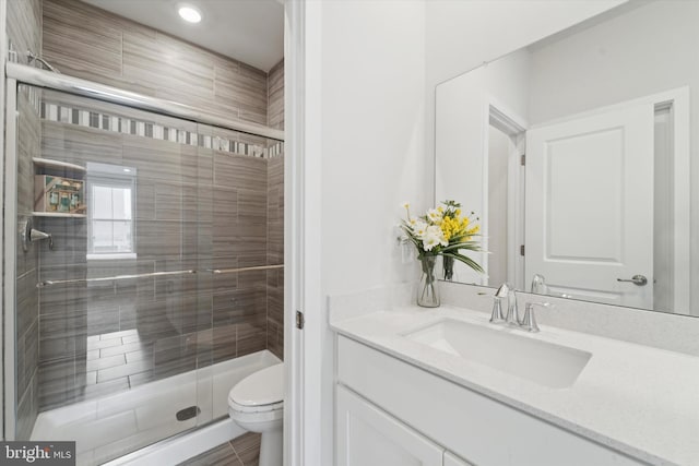 bathroom with vanity, toilet, and a shower with shower door