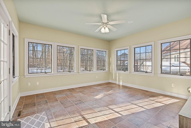 unfurnished sunroom featuring ceiling fan and a healthy amount of sunlight