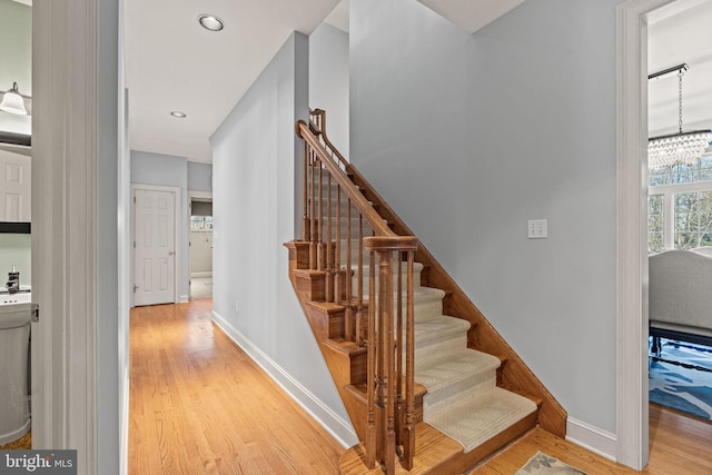 stairway featuring hardwood / wood-style flooring and an inviting chandelier