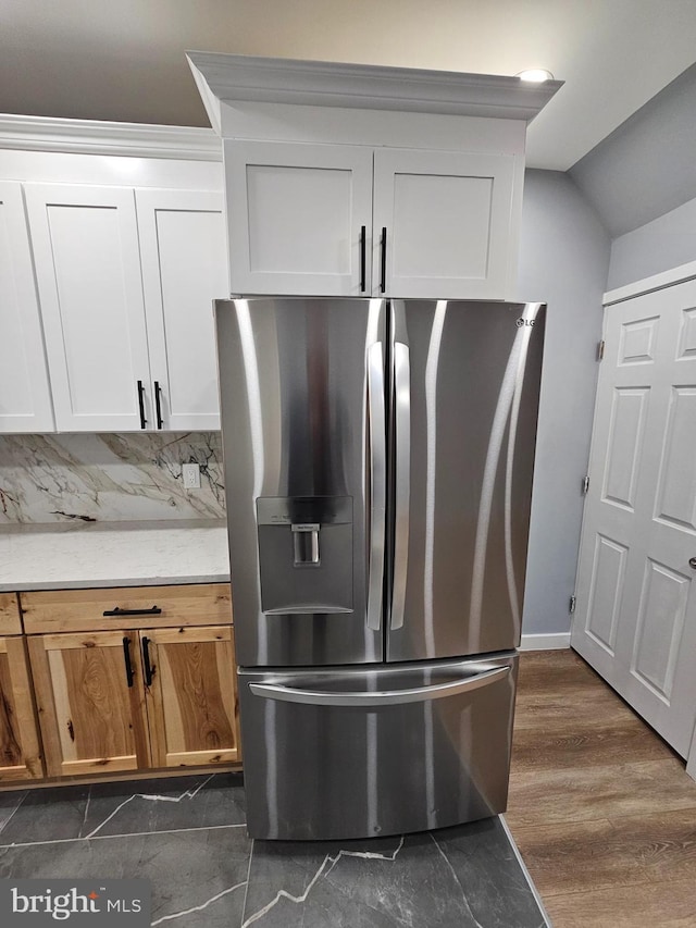 kitchen featuring backsplash, stainless steel fridge, white cabinets, and light stone countertops