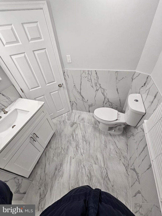 bathroom featuring vanity, toilet, and tile walls