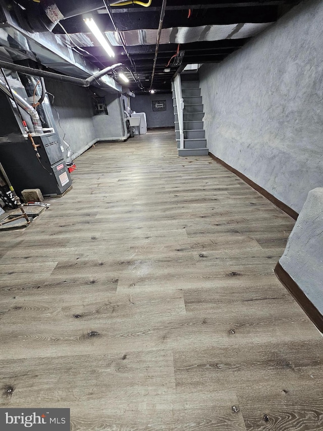 basement featuring wood-type flooring and heating unit