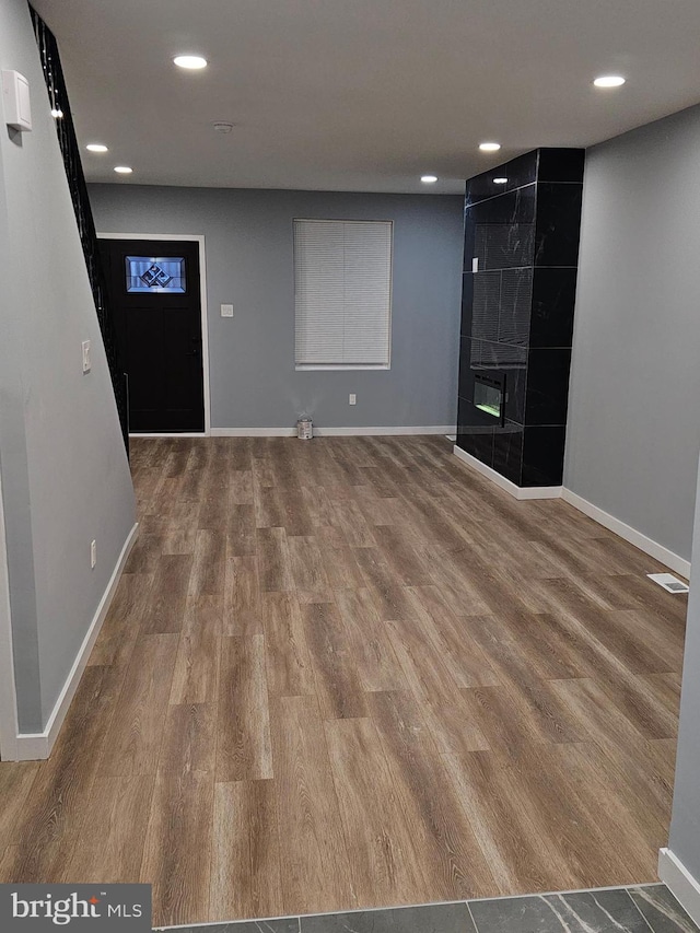 interior space with a tile fireplace and hardwood / wood-style floors