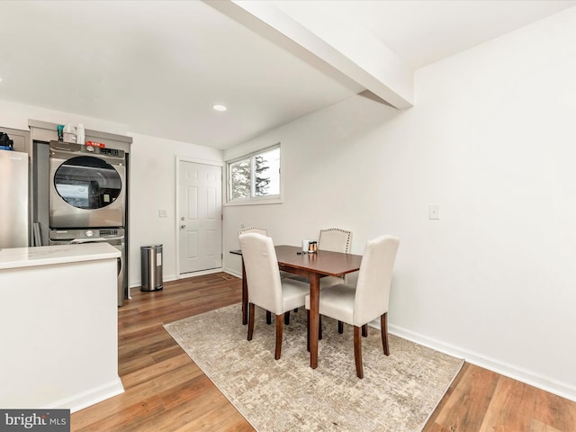 dining space featuring hardwood / wood-style flooring, beam ceiling, and stacked washing maching and dryer