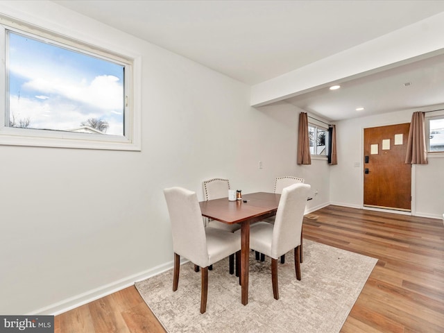 dining area featuring beam ceiling, a wealth of natural light, and light hardwood / wood-style floors