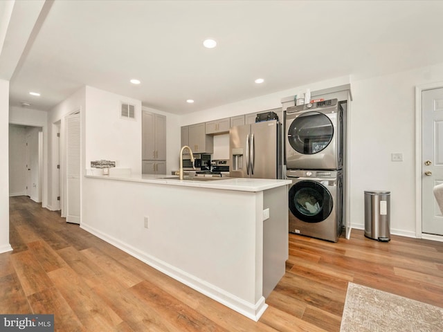 interior space with light hardwood / wood-style floors, sink, and stacked washer / dryer