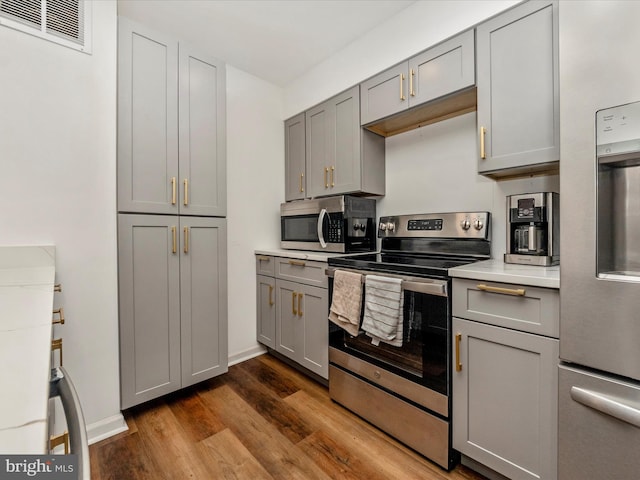 kitchen with gray cabinetry, dark hardwood / wood-style flooring, and appliances with stainless steel finishes