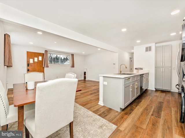 kitchen with gray cabinets, dishwasher, sink, and light hardwood / wood-style floors