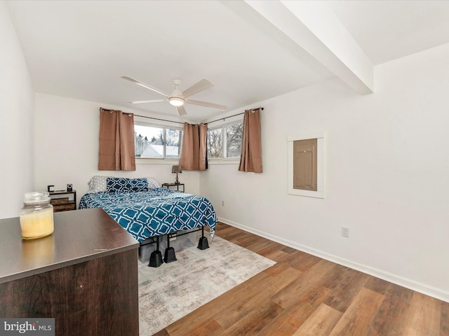 bedroom with ceiling fan, beamed ceiling, and wood-type flooring