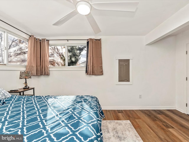 bedroom featuring multiple windows, ceiling fan, electric panel, and wood-type flooring